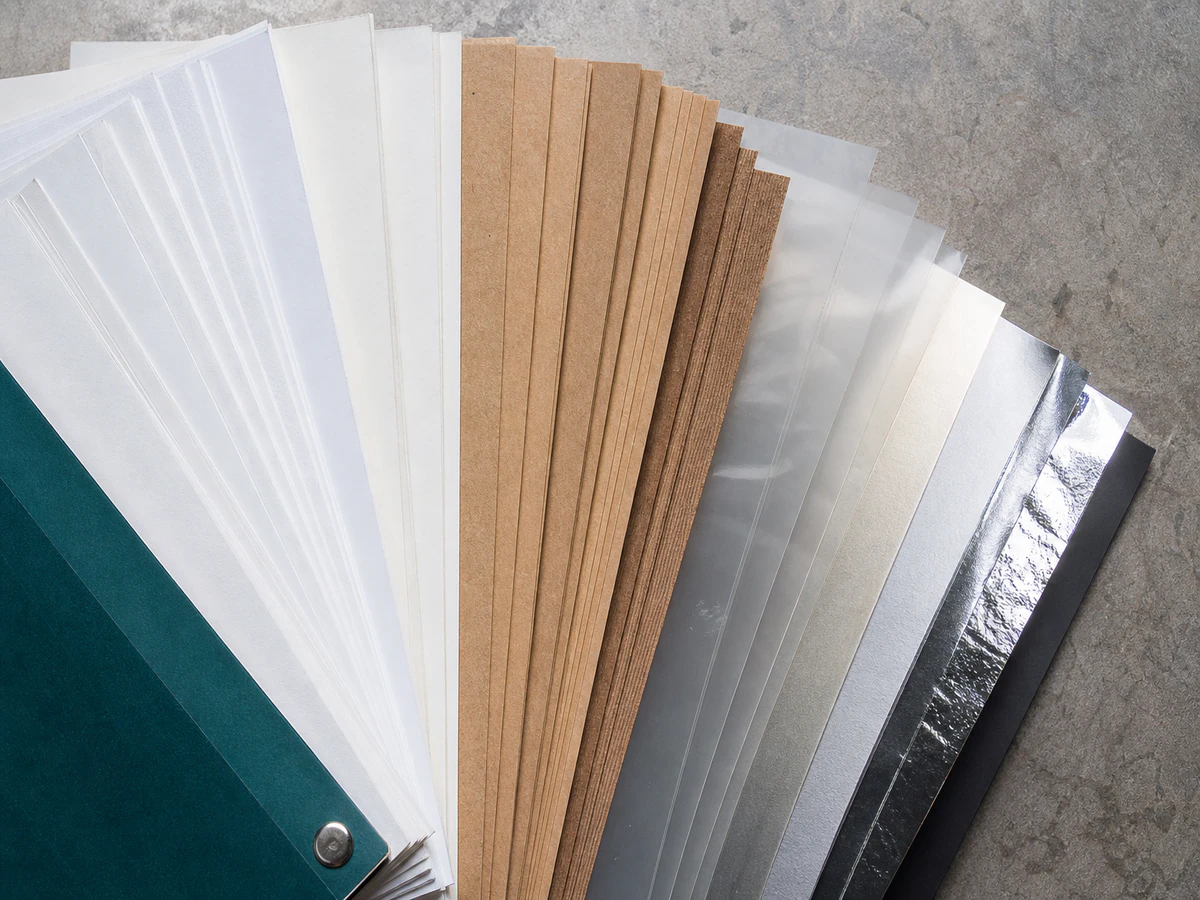 A fan of face stock swatches showing coated, kraft, clear film and foil surfaces