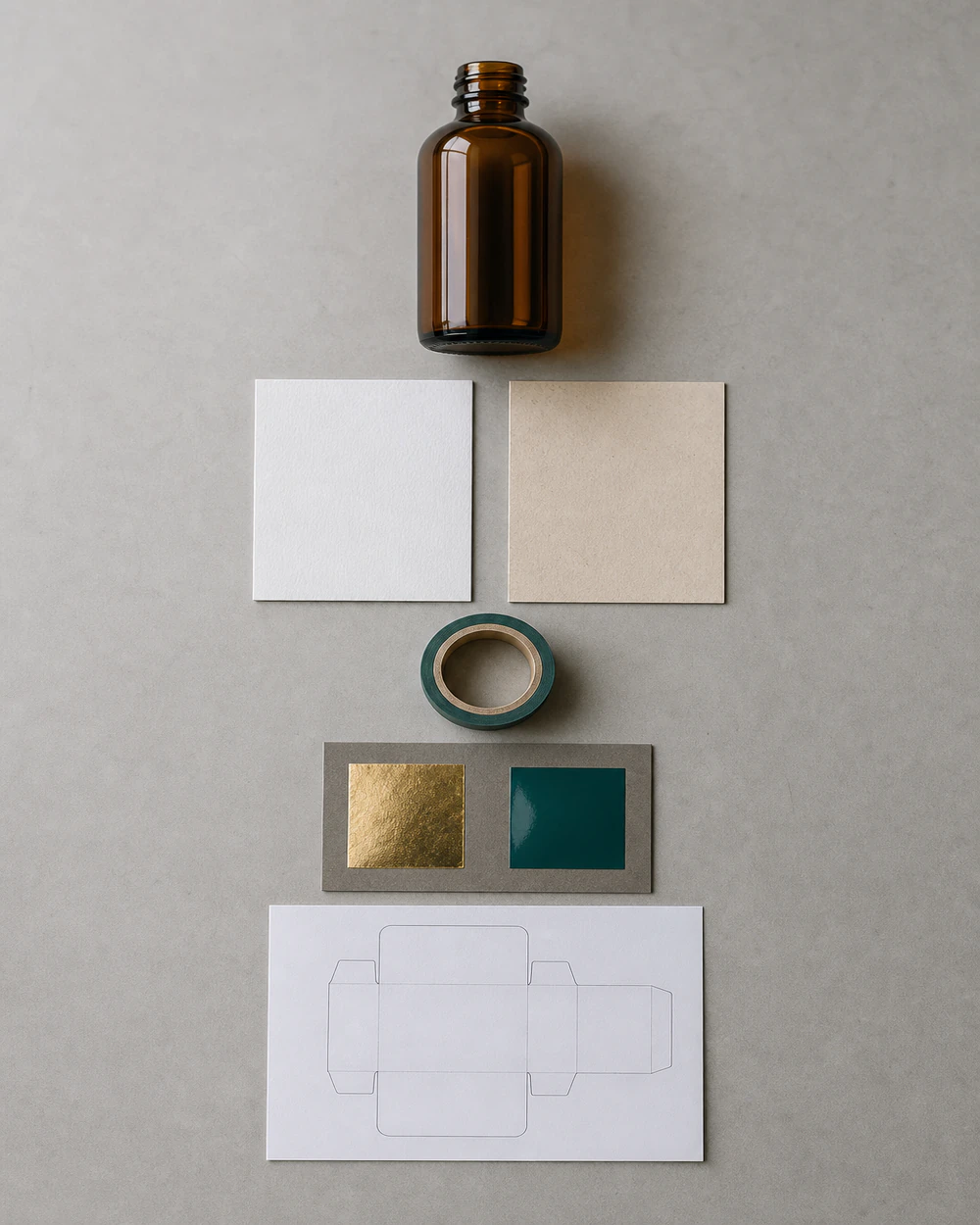 The decision items laid out in order on a bench: an empty container, face swatches, an adhesive sample and a dieline print
