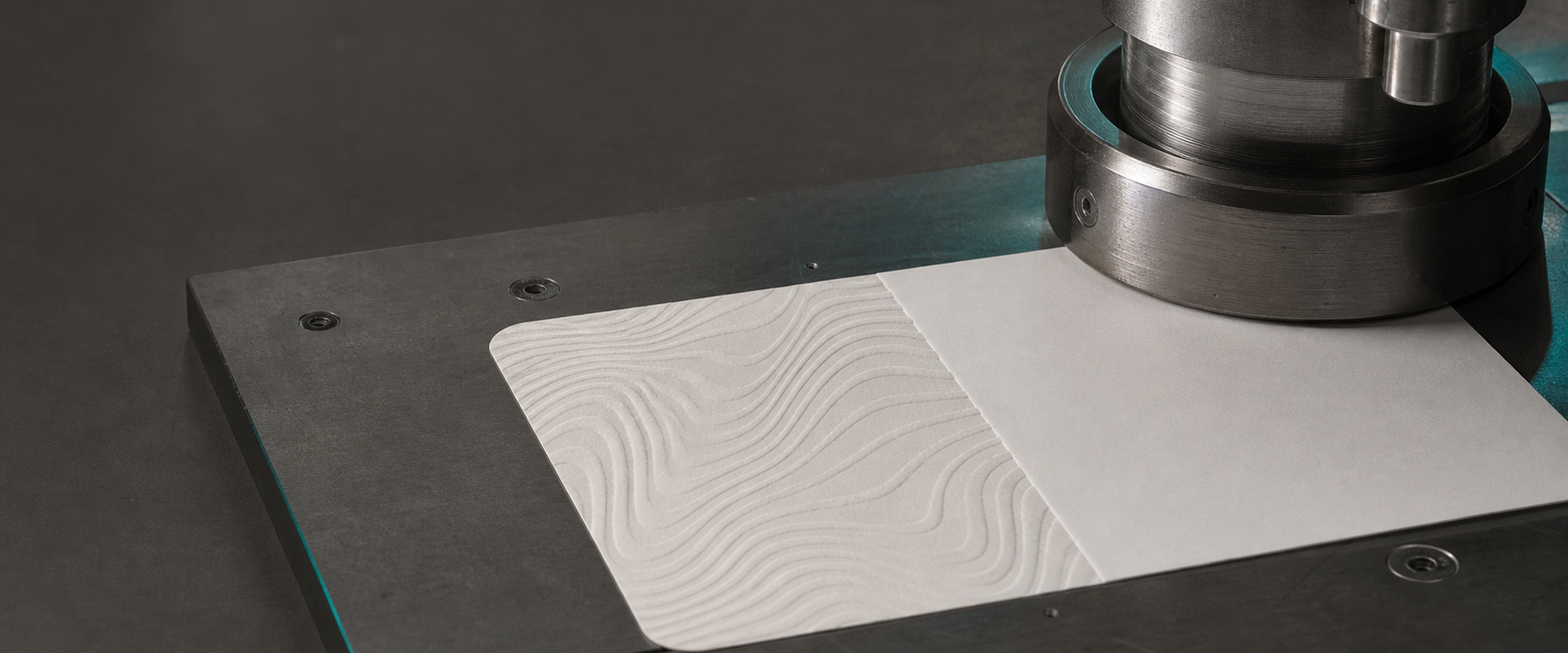 Close view of an embossing die pressing a single label, the head stopping part-way and leaving an unpressed plain band